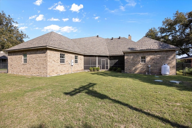 rear view of house with a yard and a sunroom