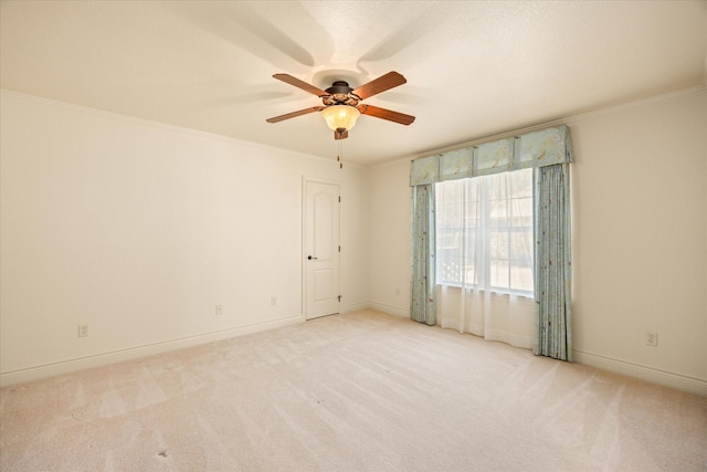 carpeted spare room featuring baseboards, ornamental molding, and ceiling fan