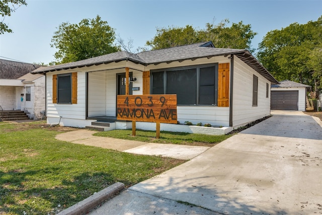 ranch-style home featuring a front yard, a garage, a porch, and an outbuilding