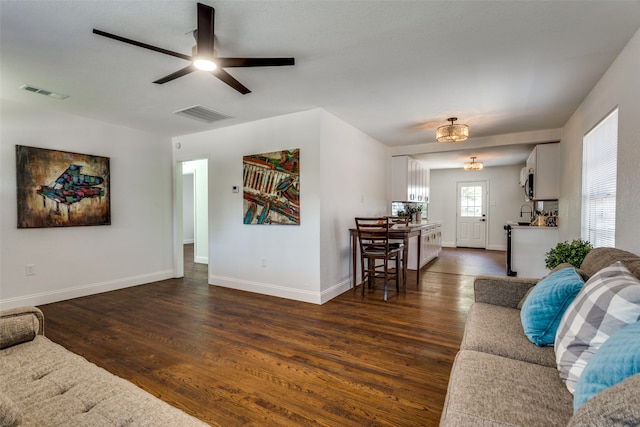 living room featuring ceiling fan and dark wood-type flooring