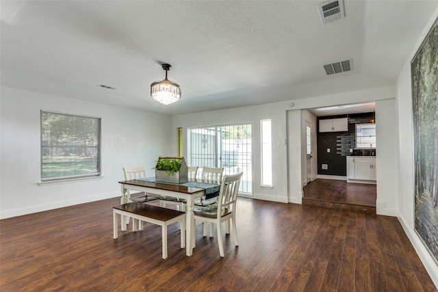 dining space featuring dark wood-type flooring and a chandelier