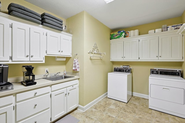 clothes washing area with cabinets, sink, and washing machine and clothes dryer