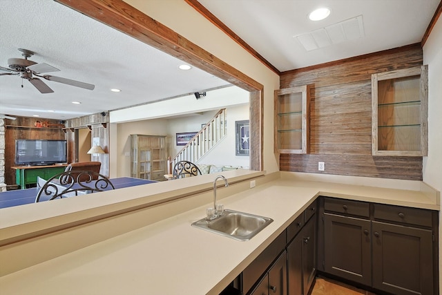 kitchen featuring dark brown cabinetry, ceiling fan, sink, kitchen peninsula, and crown molding