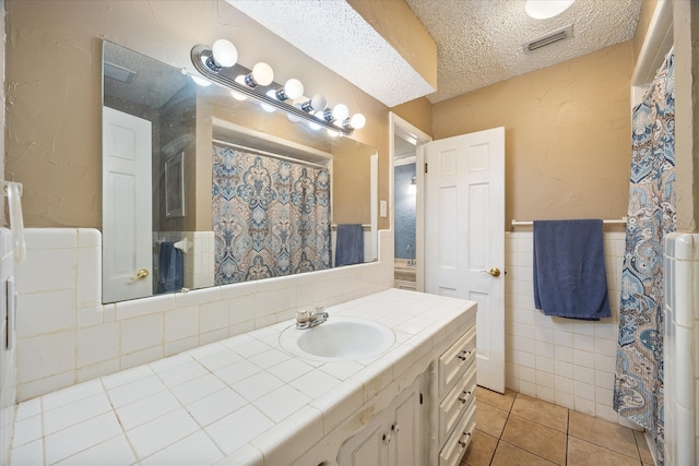 bathroom featuring tile walls, vanity, a textured ceiling, and tile patterned floors