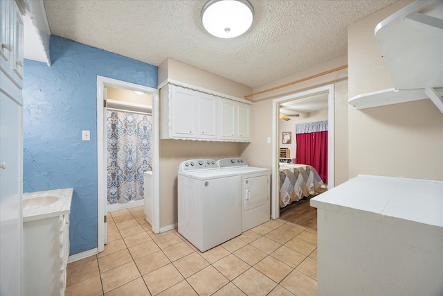 washroom featuring washer and dryer, a textured ceiling, cabinets, and light tile patterned floors