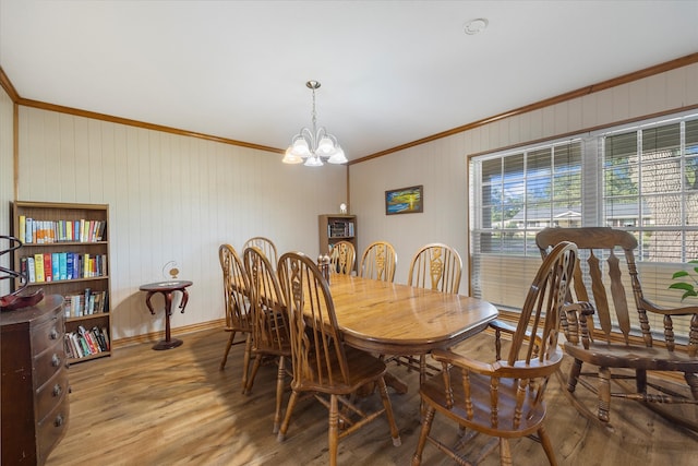 dining room featuring hardwood / wood-style floors, crown molding, an inviting chandelier, and wood walls