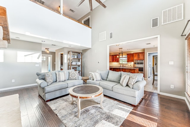 living room featuring a towering ceiling, dark hardwood / wood-style floors, a chandelier, and sink