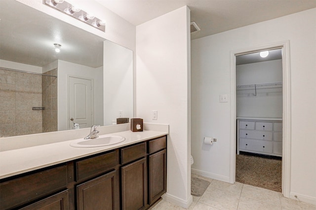 bathroom featuring a tile shower, vanity, toilet, and tile patterned floors