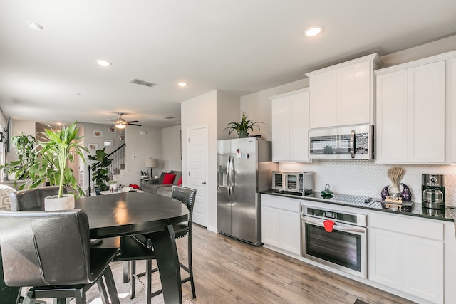 kitchen with backsplash, white cabinetry, light hardwood / wood-style floors, and appliances with stainless steel finishes