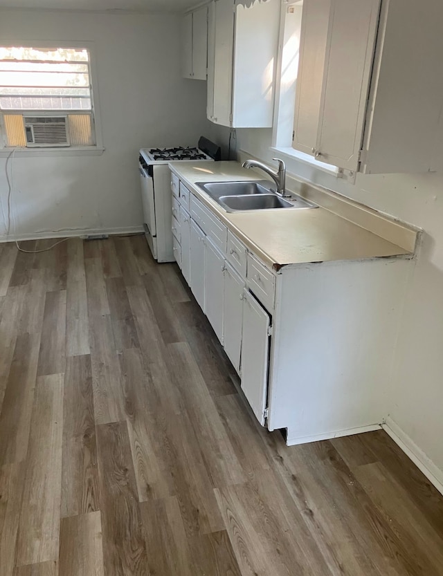 kitchen with cooling unit, wood-type flooring, white gas range oven, sink, and white cabinets