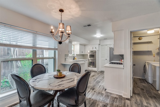 dining area with hardwood / wood-style floors, separate washer and dryer, a notable chandelier, and sink