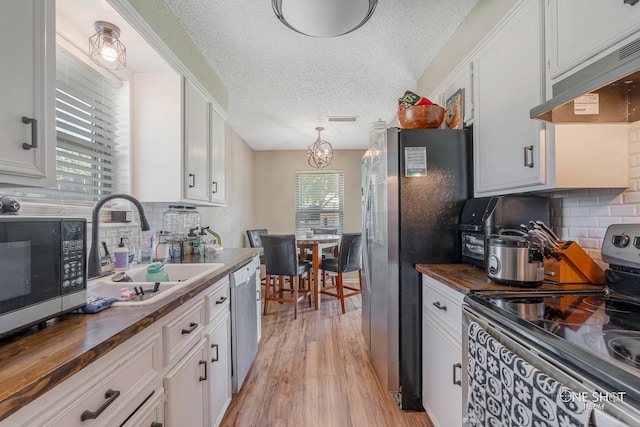 kitchen with visible vents, appliances with stainless steel finishes, a sink, butcher block counters, and under cabinet range hood
