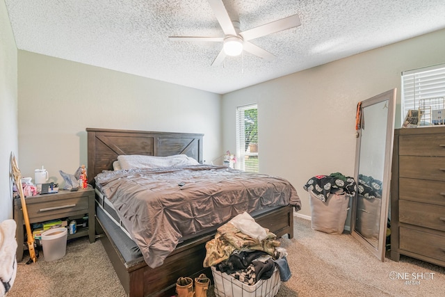 carpeted bedroom featuring a ceiling fan and a textured ceiling