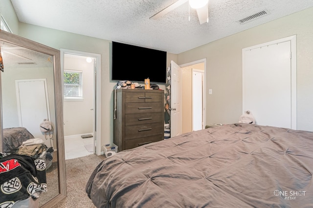 carpeted bedroom with ceiling fan and a textured ceiling