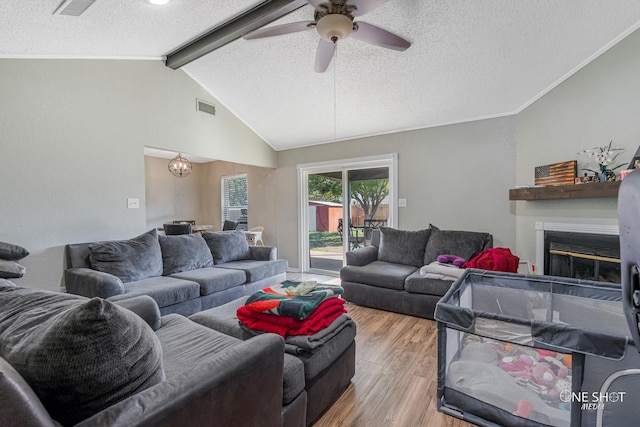 living room with ceiling fan with notable chandelier, lofted ceiling with beams, a textured ceiling, and light wood-type flooring