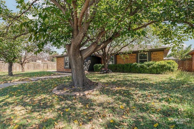 obstructed view of property featuring fence, a front yard, and brick siding