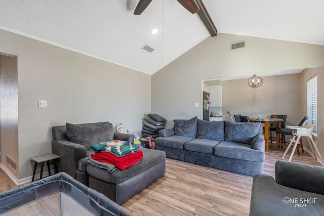 living room featuring ceiling fan, lofted ceiling with beams, a textured ceiling, and hardwood / wood-style flooring