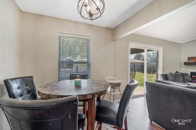 dining space with a textured ceiling, wood finished floors, and a chandelier