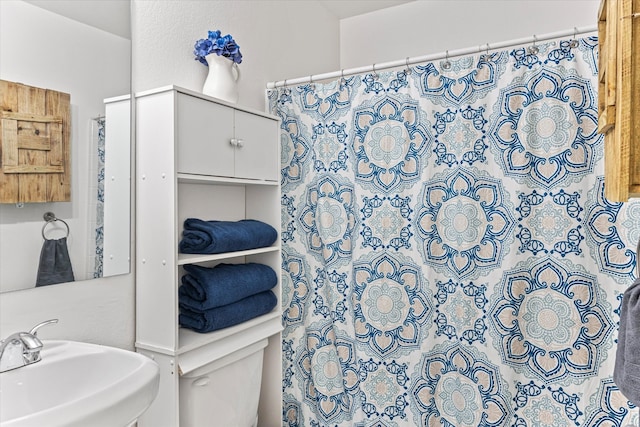 bathroom featuring toilet, sink, and walk in shower