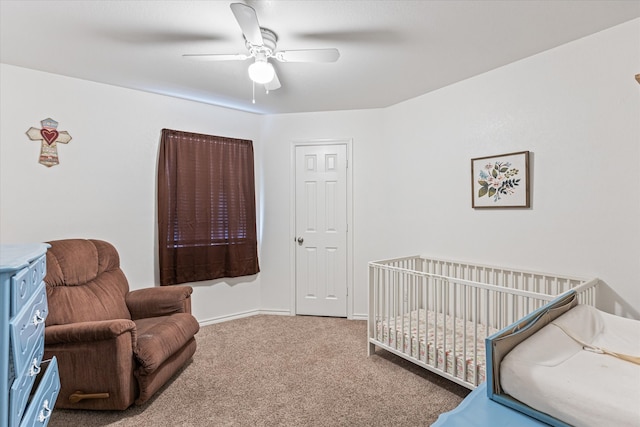 carpeted bedroom with ceiling fan and a crib