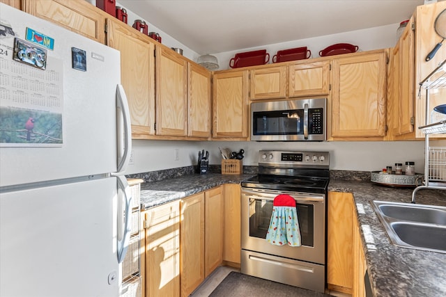 kitchen with stainless steel appliances, dark stone countertops, and sink