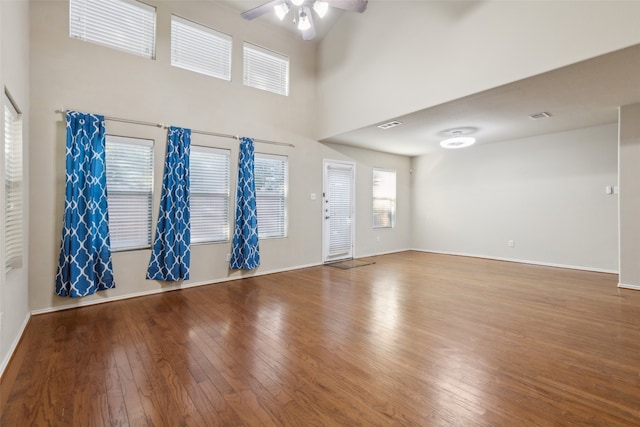 interior space with a high ceiling, wood-type flooring, and ceiling fan