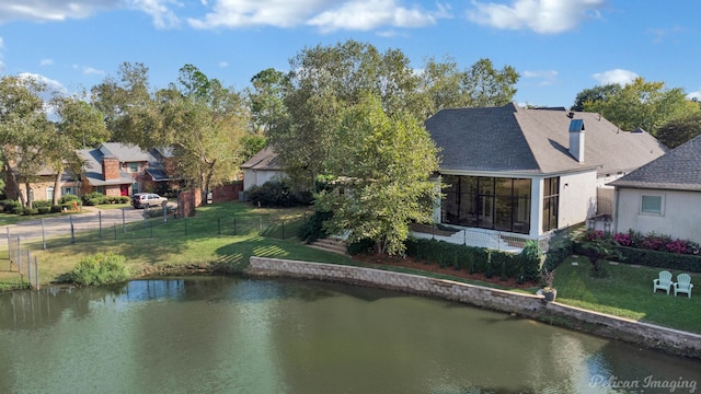 rear view of house with a water view, a sunroom, and a yard