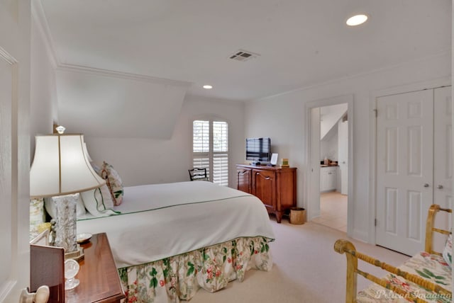 bedroom featuring a closet, crown molding, connected bathroom, and light carpet