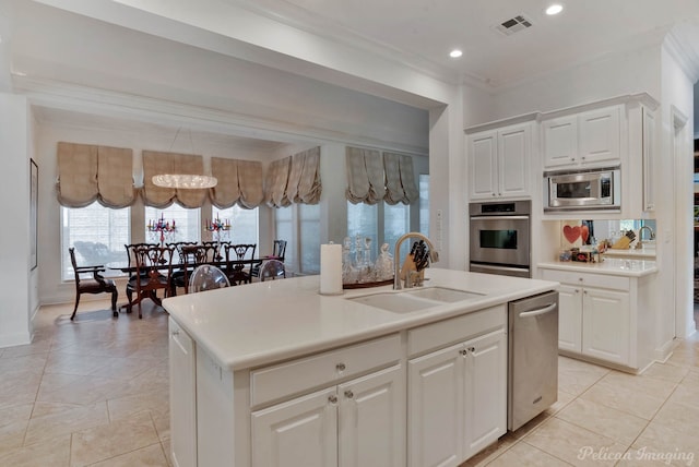 kitchen with crown molding, a center island with sink, sink, stainless steel appliances, and white cabinetry