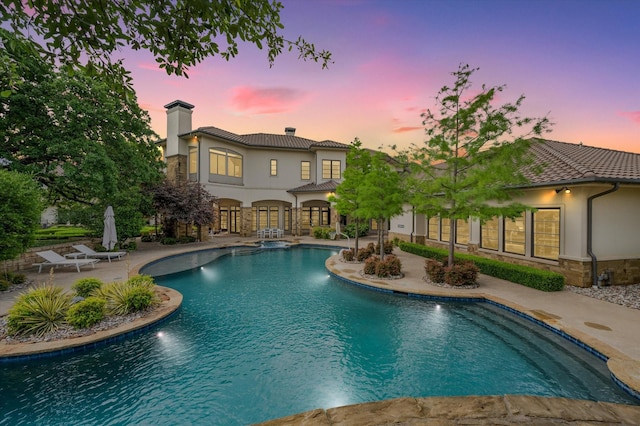 pool at dusk with a patio area