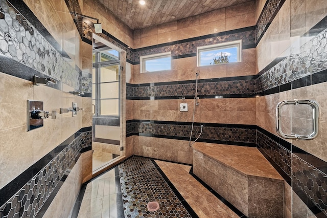 bathroom with walk in shower, tile patterned floors, and tile walls