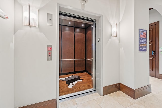 hallway with light tile patterned flooring and elevator