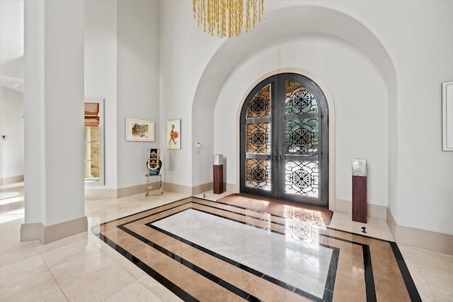 entrance foyer featuring an inviting chandelier, french doors, and a high ceiling