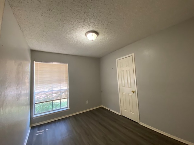 spare room with dark wood-type flooring and a textured ceiling