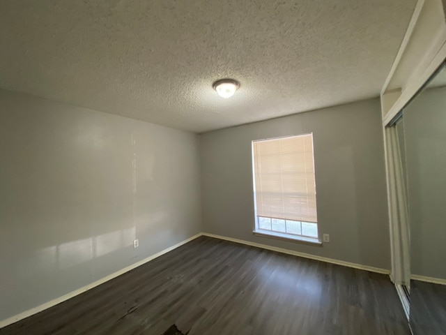 spare room with dark wood-type flooring and a textured ceiling