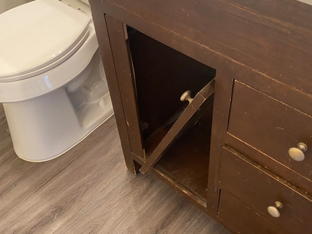 interior details featuring toilet and hardwood / wood-style floors