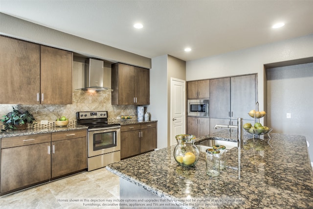 kitchen featuring wall chimney exhaust hood, stainless steel appliances, dark stone countertops, sink, and decorative backsplash