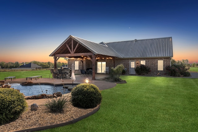 back house at dusk with a lawn and a patio area