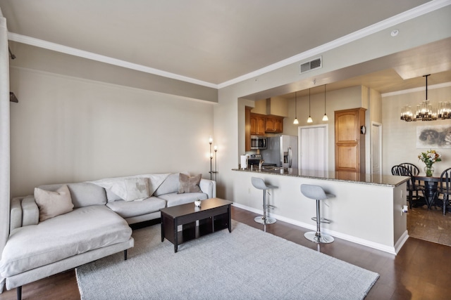 living room featuring sink, dark hardwood / wood-style floors, ornamental molding, and a chandelier