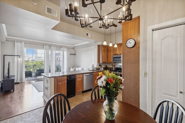 kitchen with sink, kitchen peninsula, a chandelier, appliances with stainless steel finishes, and decorative light fixtures