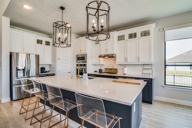 kitchen featuring an island with sink, stainless steel appliances, and white cabinets