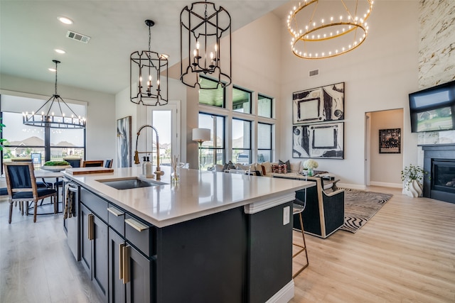 kitchen with an island with sink, light hardwood / wood-style flooring, sink, and a healthy amount of sunlight