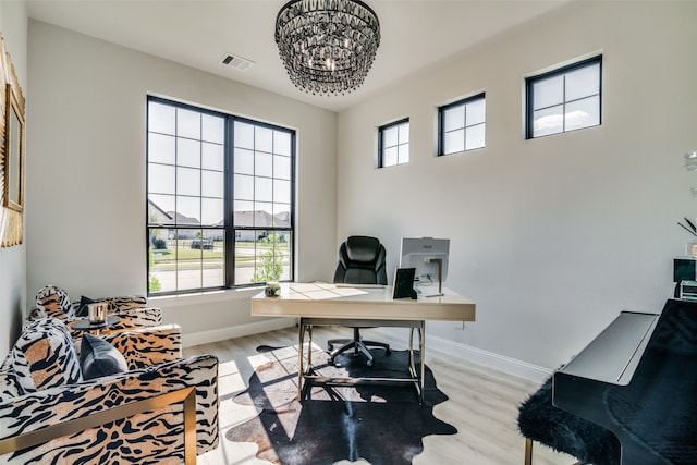 home office with plenty of natural light, light hardwood / wood-style floors, and a chandelier