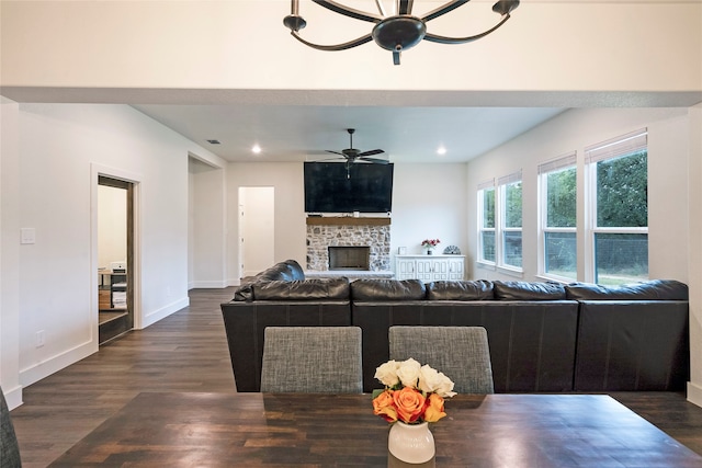 dining room featuring ceiling fan, a stone fireplace, and dark hardwood / wood-style floors