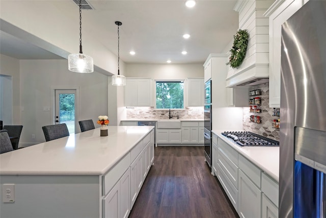 kitchen with a kitchen island, dark hardwood / wood-style flooring, white cabinetry, appliances with stainless steel finishes, and decorative light fixtures