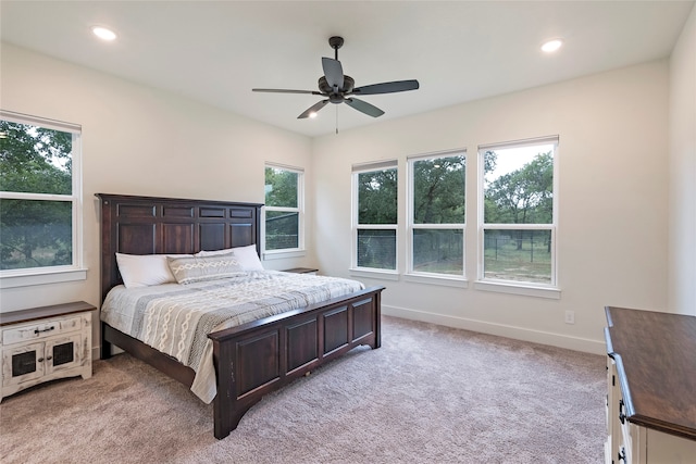 carpeted bedroom featuring multiple windows and ceiling fan