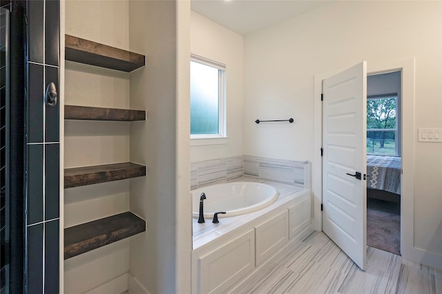 bathroom with a tub to relax in and a healthy amount of sunlight