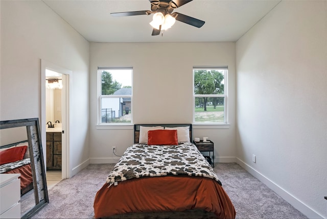 carpeted bedroom featuring ensuite bathroom, multiple windows, and ceiling fan