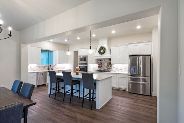 kitchen with white cabinets, appliances with stainless steel finishes, custom range hood, and a kitchen island