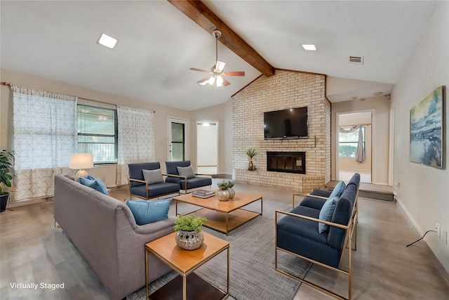 living room featuring a fireplace, vaulted ceiling with beams, light hardwood / wood-style flooring, and a wealth of natural light